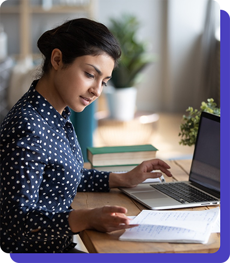 Image of woman looking at her computer and also some papers